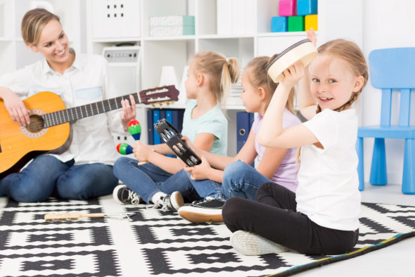 image of the adult lady playing guitar to the kids